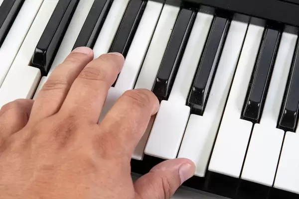 Hand spielt auf weißen und schwarzen Keyboardtasten