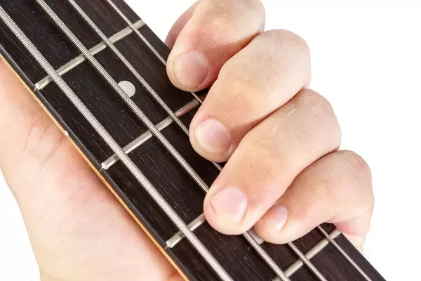 Hand spielt die Saiten einer Bassgitarre in der Nahaufnahme