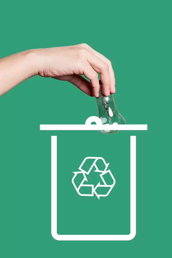 Hand throwing a light bulb. Concept of recycling