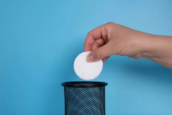 Hand throwing cotton pad in the trash