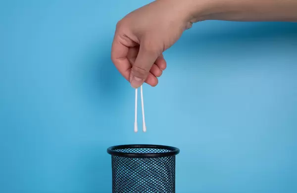 Hand throwing cotton swabs in the trash