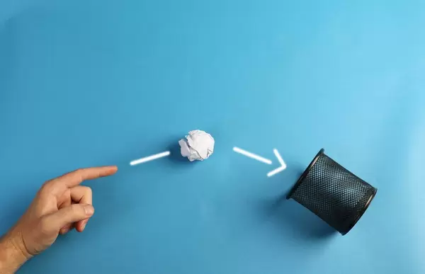 Hand throwing crumpled paper in basket