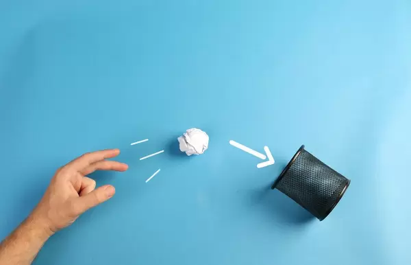 Hand throwing crumpled paper to trash