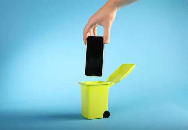 Hand throwing mobile phone into trash can