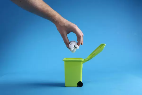 Hand throwing plastic bag into trash can