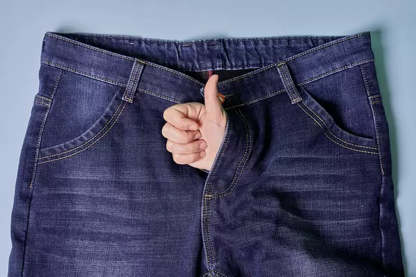 Hand thumb raised from jeans. Treatment of erectile dysfunction and sexual disorders