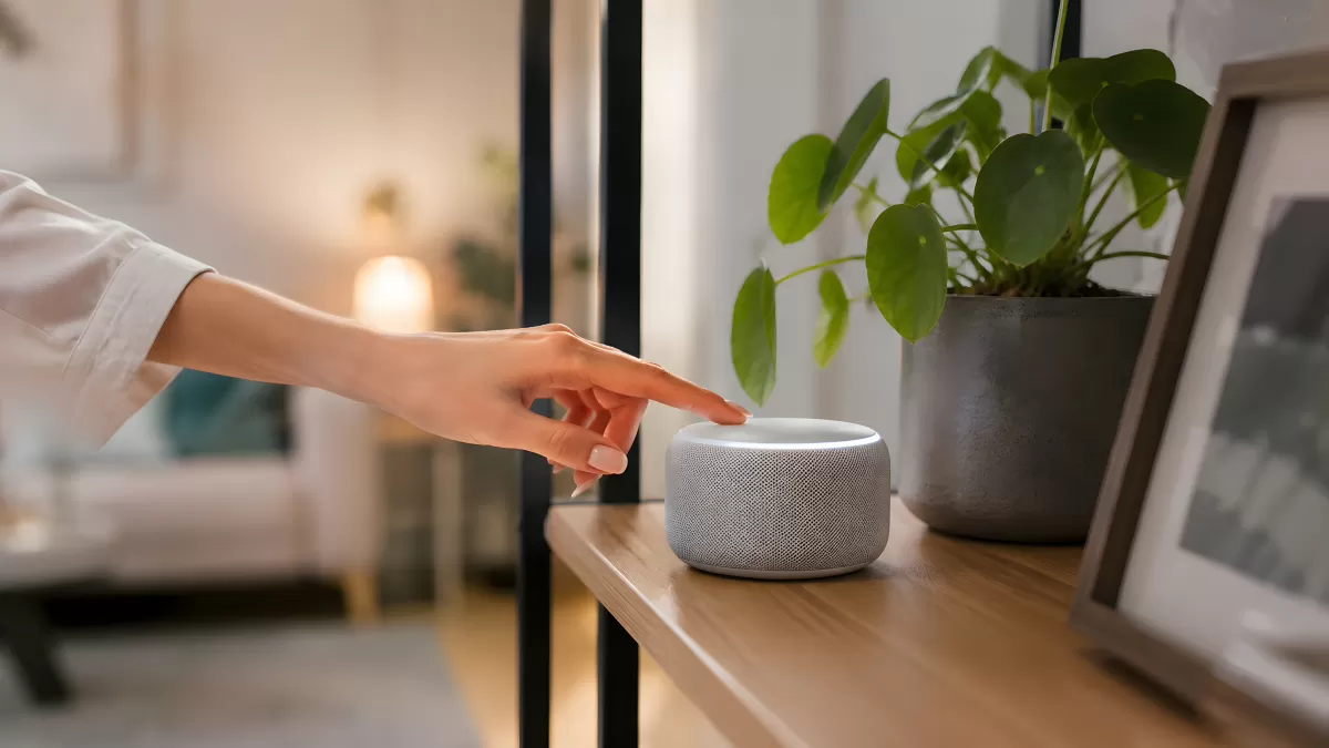 Hand tippt auf smarten Lautsprecher im Wohnzimmer