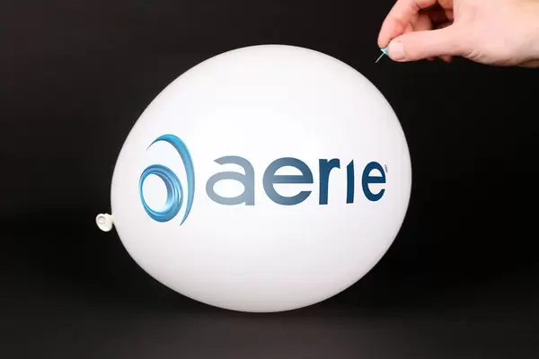 Hand uses a needle to burst a balloon with Aerie Pharmaceuticals logo