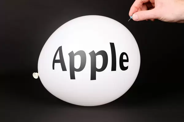Hand uses a needle to burst a balloon with Apple text