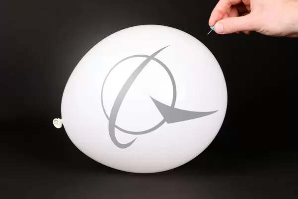 Hand uses a needle to burst a balloon with Boeing icon