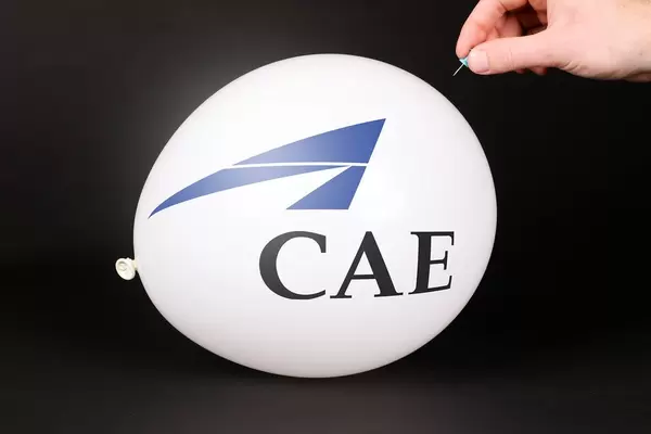 Hand uses a needle to burst a balloon with CAE logo