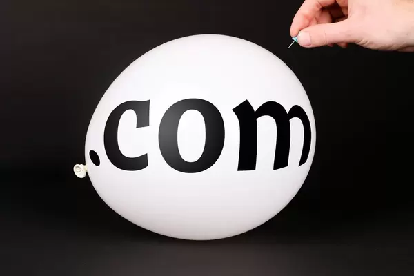 Hand uses a needle to burst a balloon with .com text