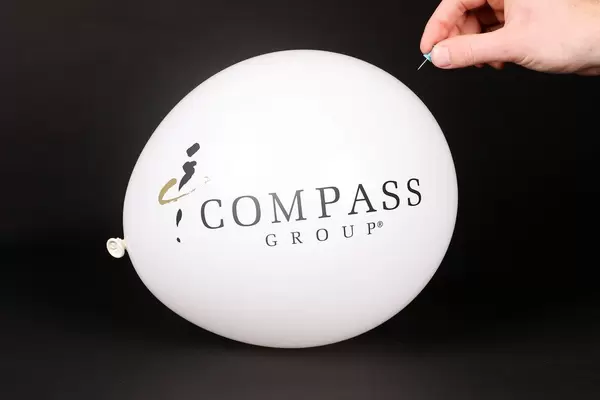 Hand uses a needle to burst a balloon with Copass Group logo