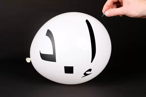 Hand uses a needle to burst a balloon with Dirham Currency Symbol