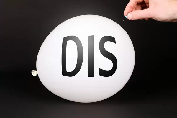 Hand uses a needle to burst a balloon with DIS text