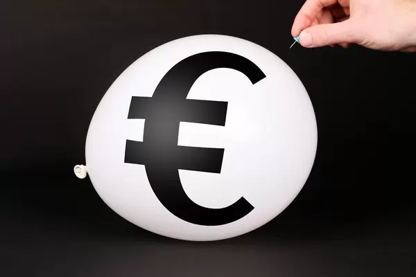 Hand uses a needle to burst a balloon with Euro symbol