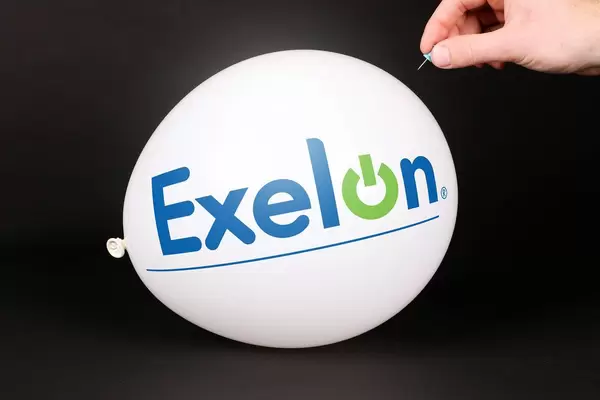 Hand uses a needle to burst a balloon with Exelon logo