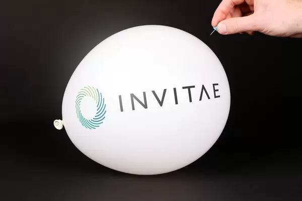 Hand uses a needle to burst a balloon with Invitae logo