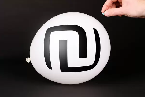 Hand uses a needle to burst a balloon with Israel Shekel symbol