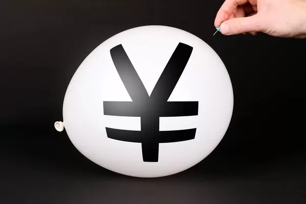 Hand uses a needle to burst a balloon with Japanese Yen symbol