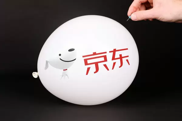 Hand uses a needle to burst a balloon with JD.com logo