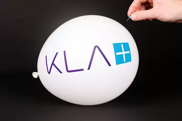 Hand uses a needle to burst a balloon with KLA logo