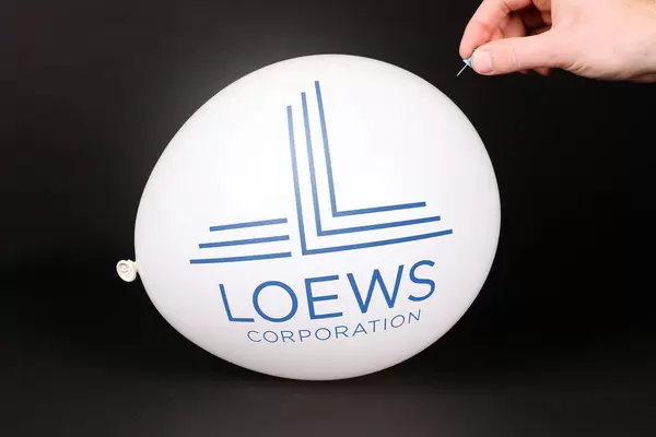 Hand uses a needle to burst a balloon with Loews logo