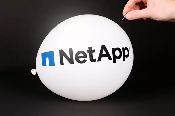 Hand uses a needle to burst a balloon with NetApp logo