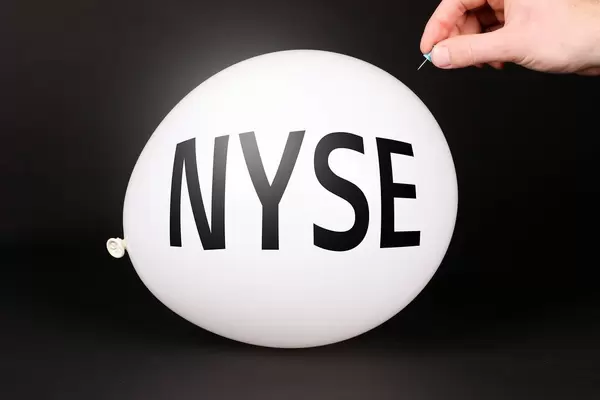 Hand uses a needle to burst a balloon with NYSE text