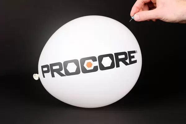 Hand uses a needle to burst a balloon with Procore logo