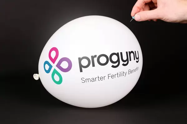 Hand uses a needle to burst a balloon with Progyny logo