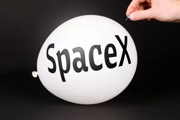 Hand uses a needle to burst a balloon with SpaceX text