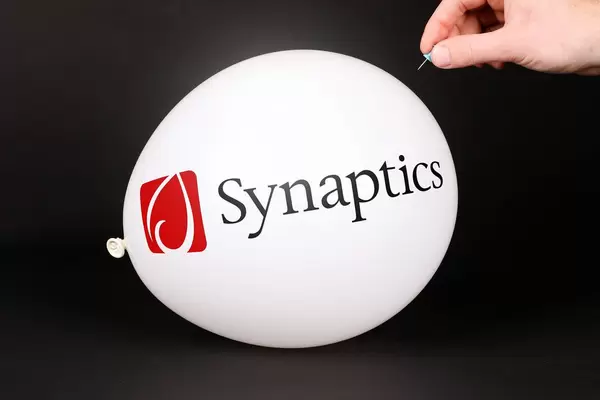 Hand uses a needle to burst a balloon with Synaptics logo