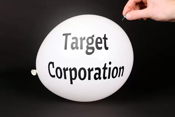 Hand uses a needle to burst a balloon with Target Corporation text
