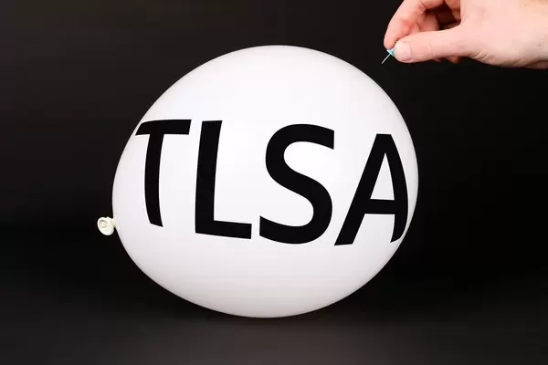 Hand uses a needle to burst a balloon with TLSA text