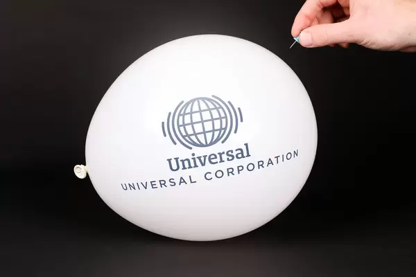 Hand uses a needle to burst a balloon with Universal Corporation logo