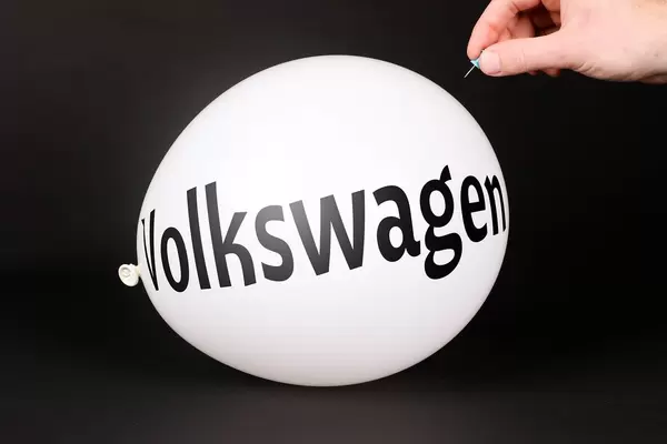 Hand uses a needle to burst a balloon with Volkswagen text