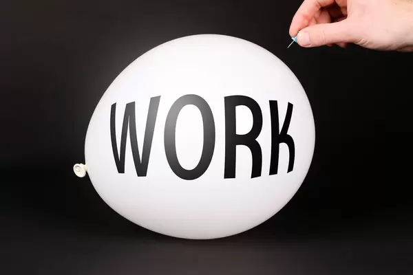 Hand uses a needle to burst a balloon with WORK text