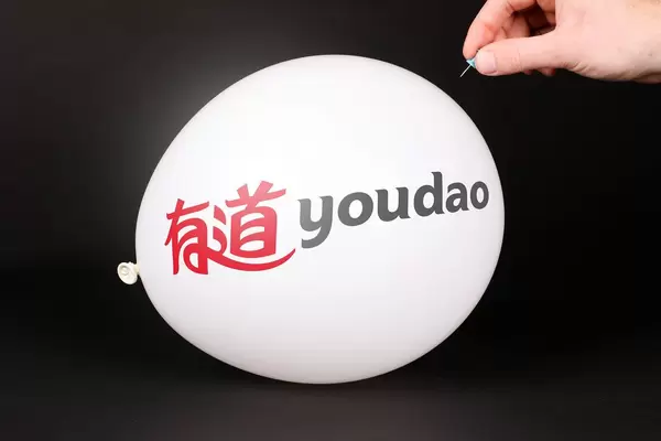 Hand uses a needle to burst a balloon with Youdao logo