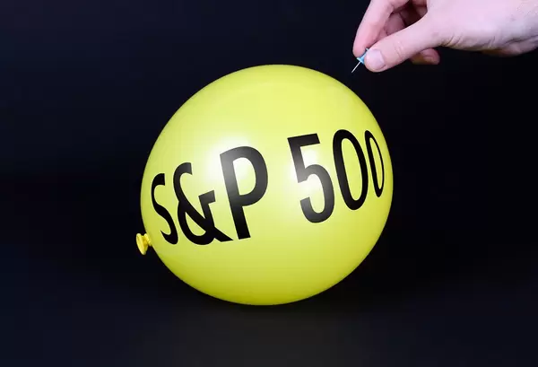 Hand uses a needle to burst a yellow balloon with S&P 500 text