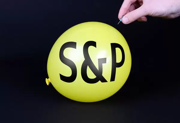 Hand uses a needle to burst a yellow balloon with S&P text