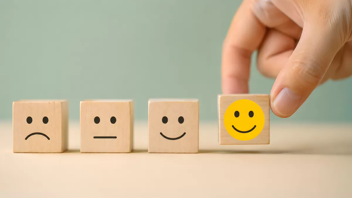Hand wählt lächelnden Emoji-Würfel aus vier Holzblöcken