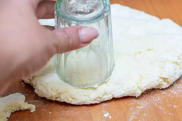 Hand with a glass cut out a circle of dough