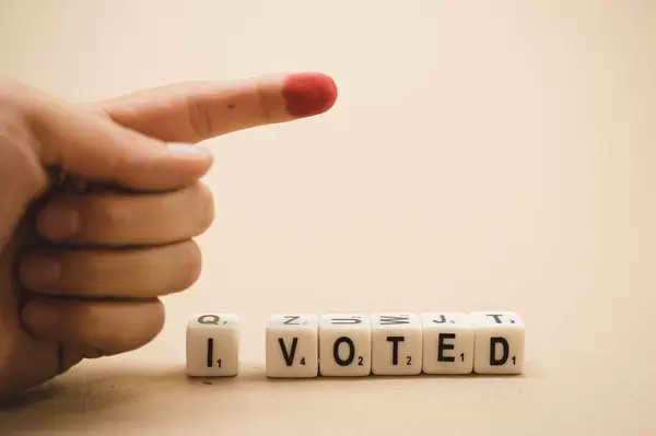 Hand with a marked finger and dice reading I VOTED
