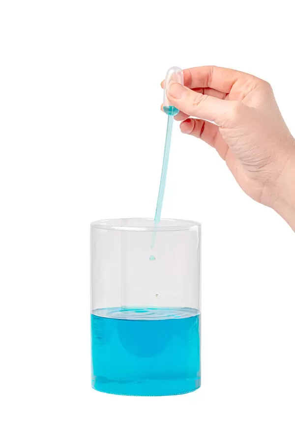 Hand with a pipette drips the solution into a plastic flask