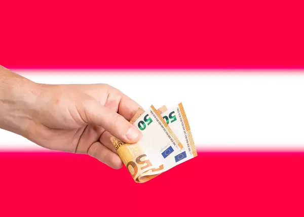 Hand with Euro banknotes over flag of Austria