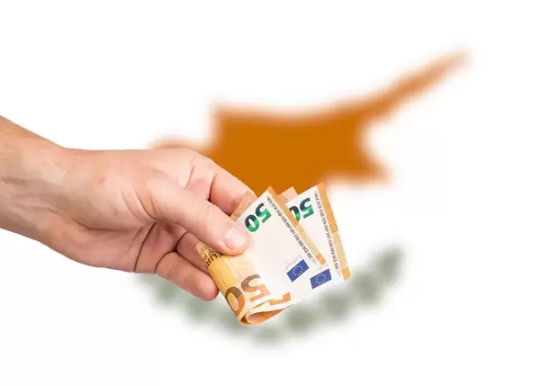 Hand with Euro banknotes over flag of Cyprus