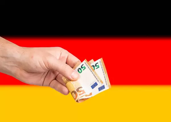Hand with Euro banknotes over flag of Germany