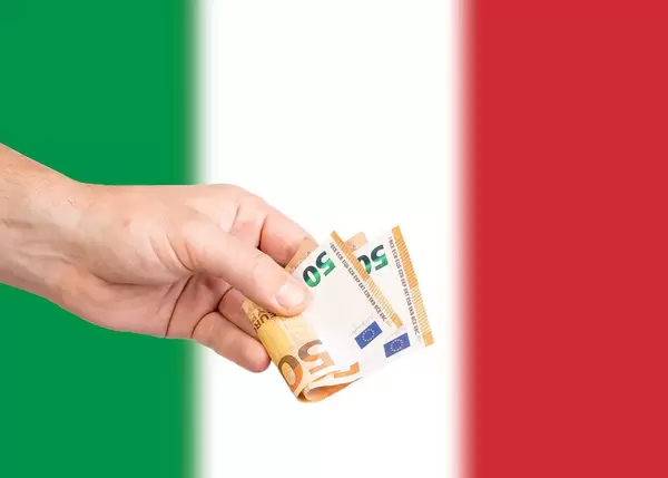 Hand with Euro banknotes over flag of Italy