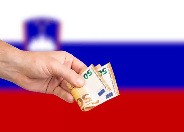 Hand with Euro banknotes over flag of Slovenia